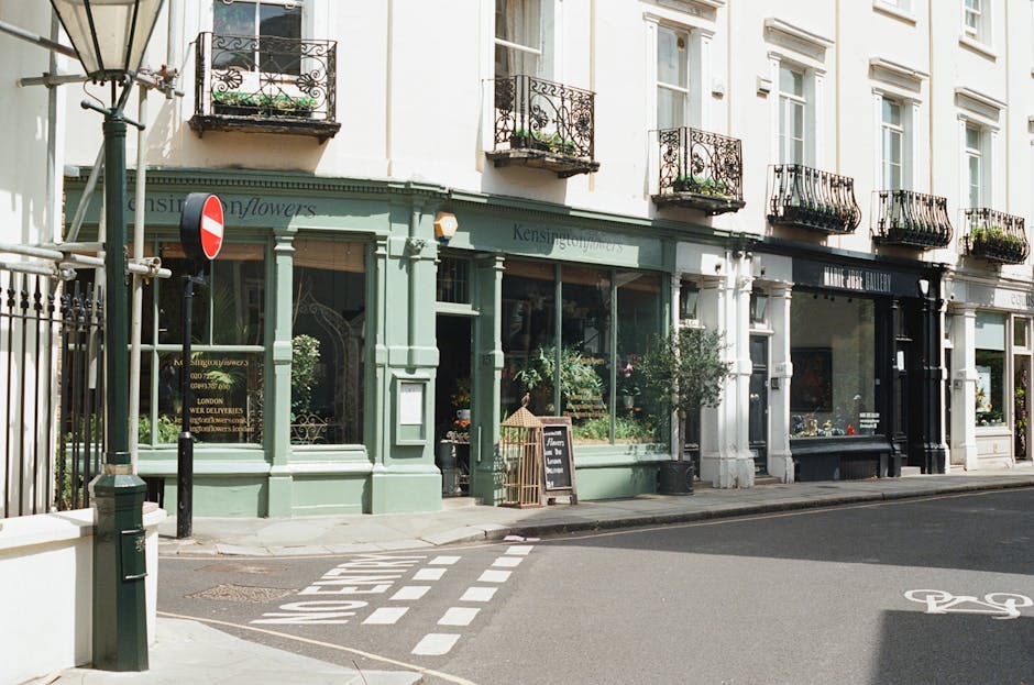 A rectangular white metal street sign mounted on a red-brown brick wall, displaying the text 'WELCOME TO SOUTH KENSINGTON SW7' in black and red lettering. The sign is positioned centrally within the f